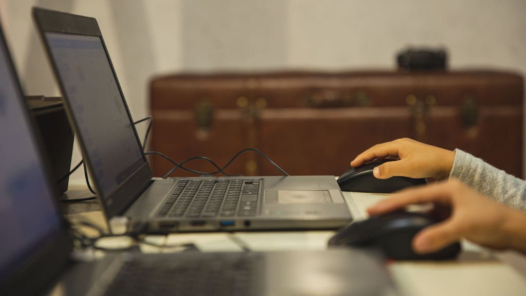 Visão lateral de laptops e equipamentos de TI sendo usados em uma mesa de trabalho.