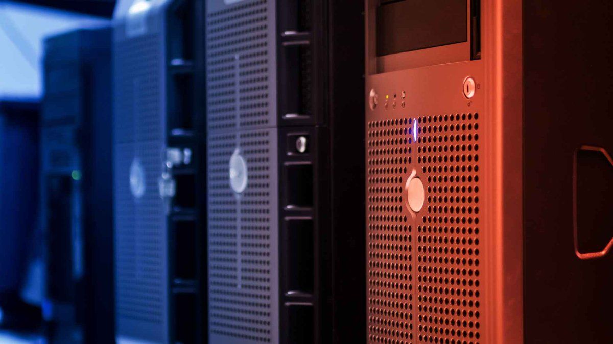 hardware de servidor em rack em primeiro plano com iluminação azul e vermelha contrastante no fundo.