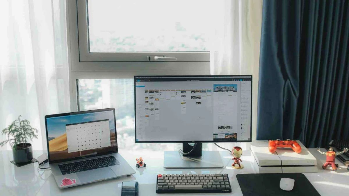 Monitor de computador, notebook e acessórios gamer como equipamentos para home office em um ambiente iluminado.