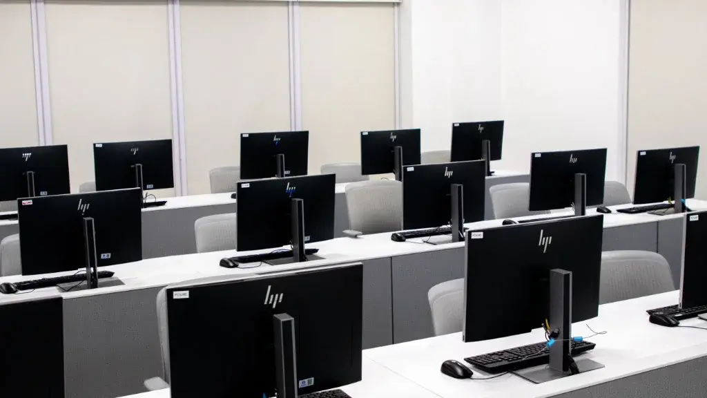 Laboratório de informática moderno com várias bancadas equipadas com computadores e cadeiras organizadas